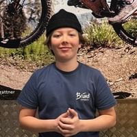 Lehrling Anton steht vor einem Poster mit Mountainbiker