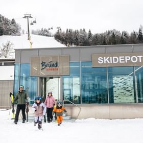 Eine Familie verlässt das Bründl Sports Skidepot in Zell am See und geht zum Skifahren