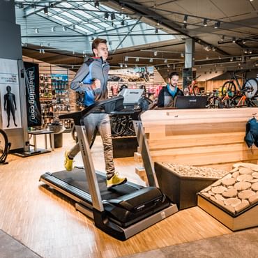 A runner is running on a treadmill which is standing inside the shop