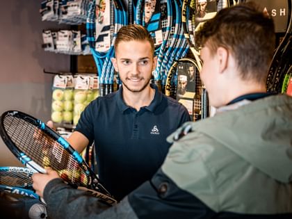 A customer gives his tennis racket to a staff member