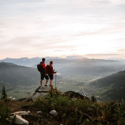 Hikers on a viewpoint with a sunset in the background
